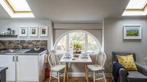 A modern kitchen with a dining area, skylights, and a view of the outdoors. - Little Brook (Weymouth)
