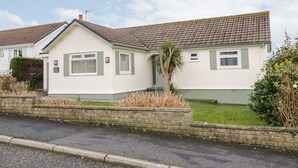 A two-story house with a tiled roof, a small front garden, and a paved driveway. - Hardy Cottage (Tyn-y-Gongl)