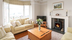 A living room with a beige sofa, a wooden coffee table, a fireplace, and a television.