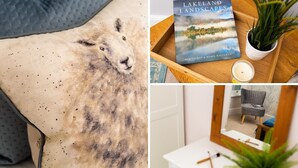 A room with a bed, a book titled 'Lakeland Landscapes' by Rob Talbot & Robin White, a potted plant, and a mirror reflecting a chair and a small table.