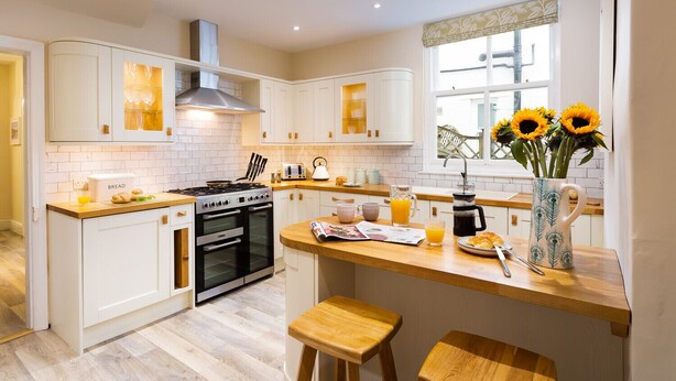 A modern kitchen with white cabinets, a stainless steel stove, and a window with sunflowers.