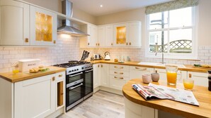 A modern kitchen with white cabinets, a gas stove, an oven, and a window with a view.