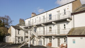 Un immeuble à plusieurs étages, avec un escalier menant aux étages supérieurs, un espace de stationnement à l’avant et un petit coin salon extérieur.