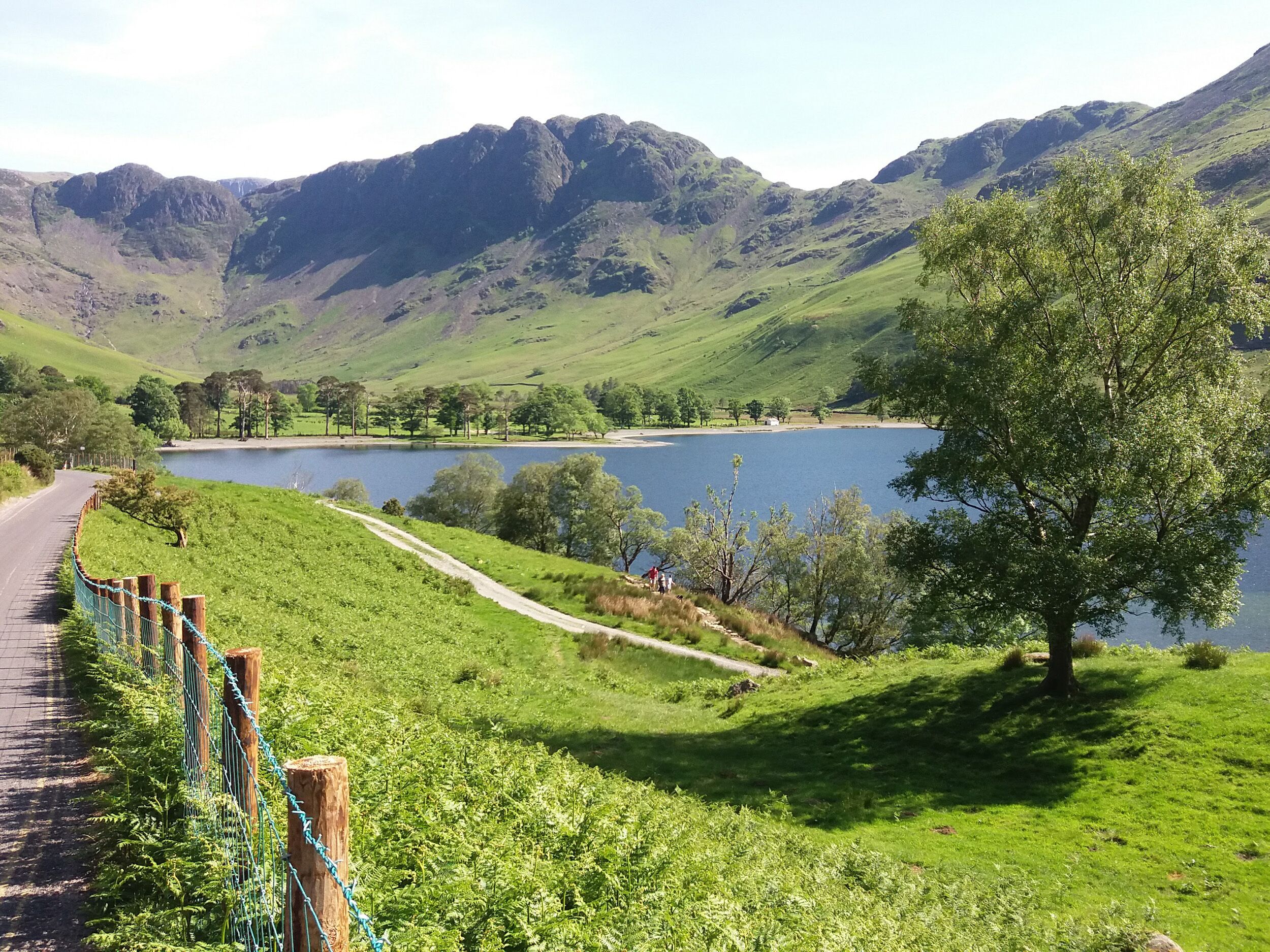 A scenic view of a lake surrounded by green hills and mountains.