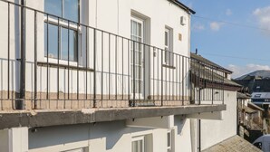Un bâtiment blanc doté d’un balcon, d’une porte et d’une fenêtre.
