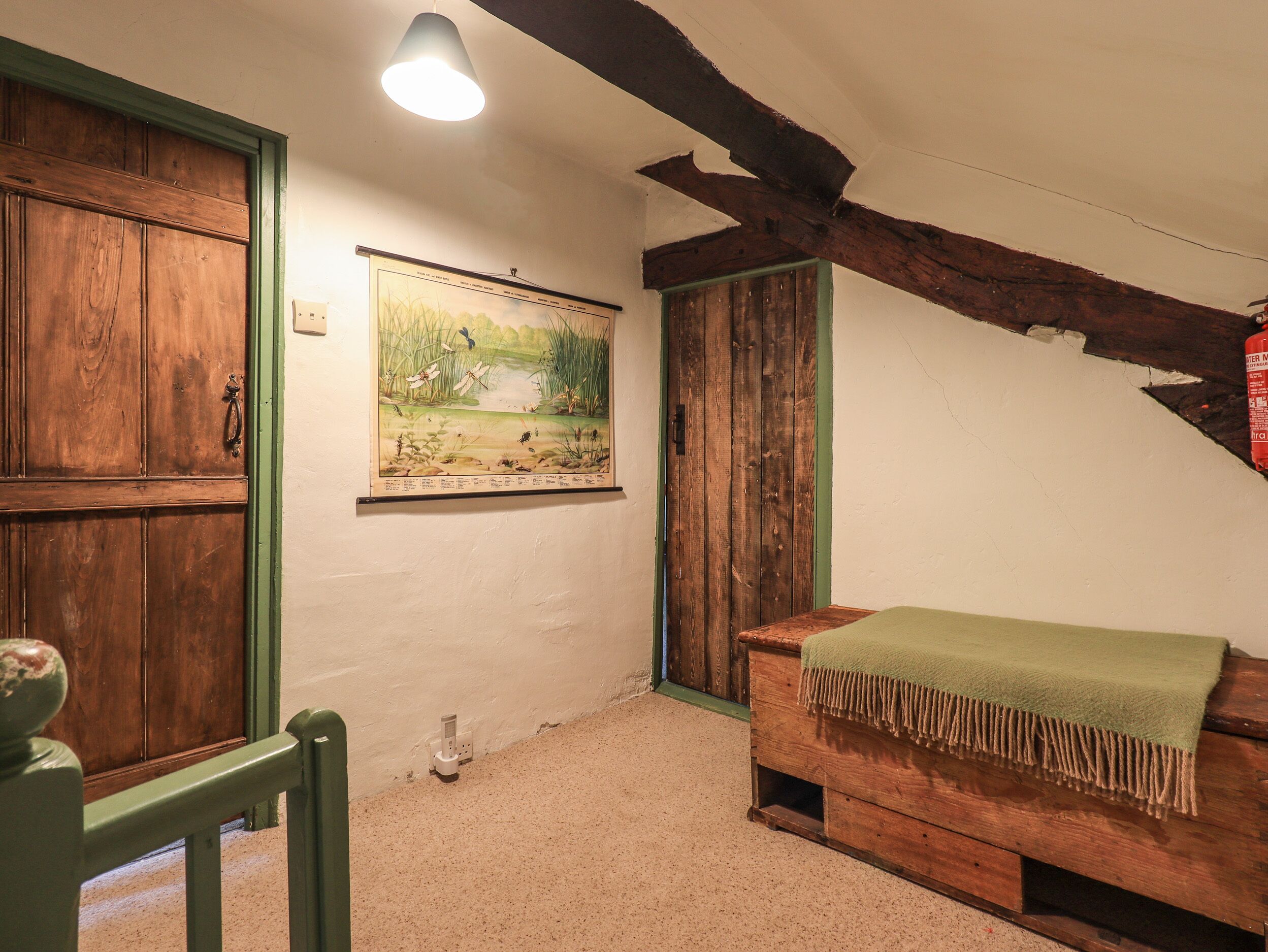 A room with a wooden bench, a framed nature painting, and a wooden door.