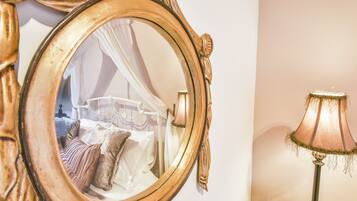 A bedroom with a bed, a bedside lamp, and a mirror reflecting the room.