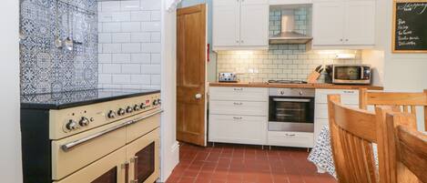 A kitchen with white cabinets, a stove, an oven, a microwave, and a chalkboard menu.