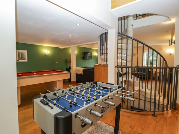 A room with a foosball table, a pool table, a sofa, and a staircase. - About Time Cottage (Lydney)