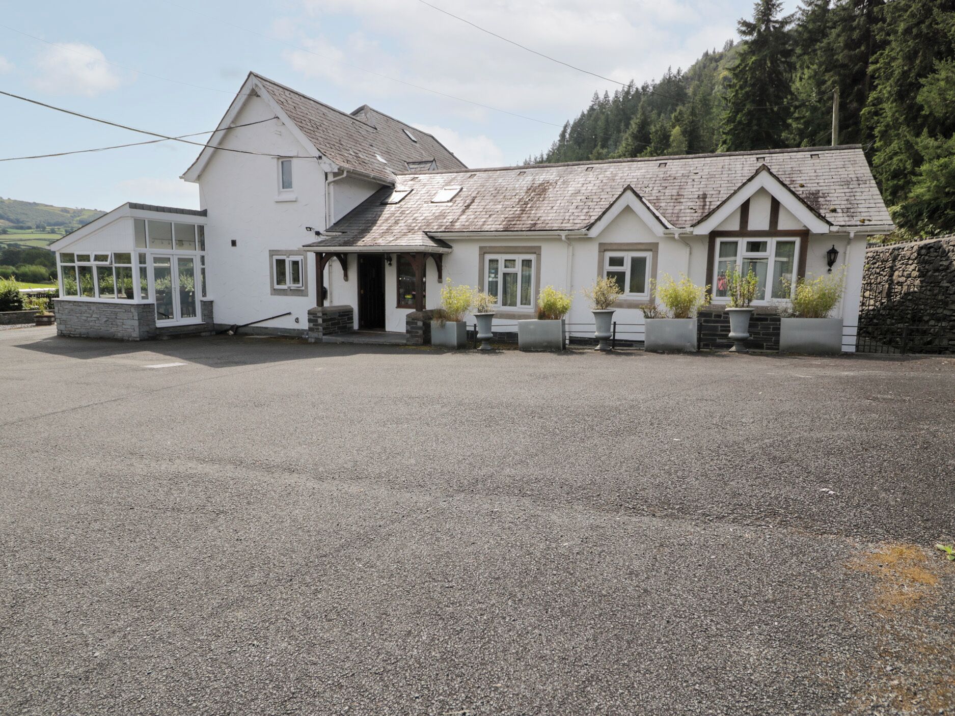 A two-story building with a gravel driveway and potted plants in front.