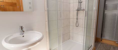 A bathroom with a glass-enclosed shower, a white sink, and a wooden cabinet.
