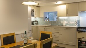 Cocina moderna con comedor, que incluye una mesa de madera, sillas y una botella de vino.