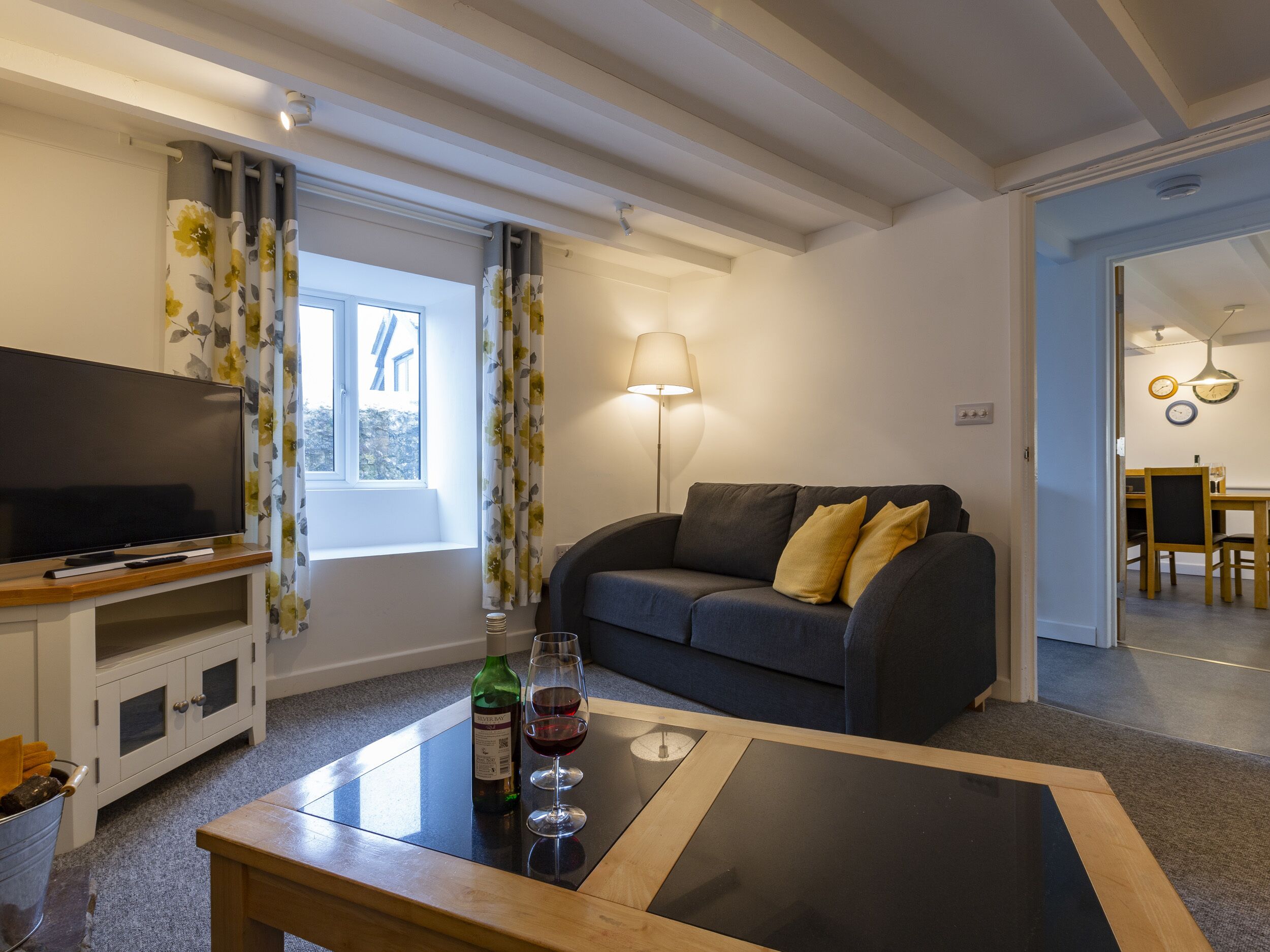 A living room with a television, sofa, and a coffee table with a bottle and glass.