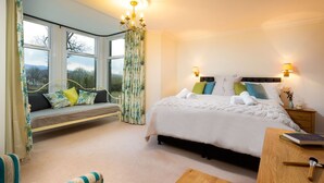 A bedroom with a large bed, a window seat, and a chandelier. - One The Howe (Keswick)