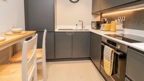 Una cocina moderna con armarios oscuros, una mesa de comedor de madera y una silla blanca.