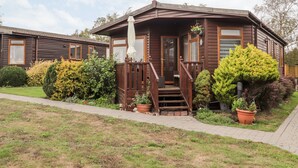 A wooden cabin with a porch, potted plants, and a pathway leading to the entrance.