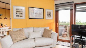 A living room with a sofa, a coffee table, a TV, and framed pictures on the wall.
