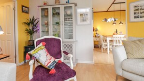 A living room with a white armchair, a purple throw blanket, and a cabinet with glass doors.
