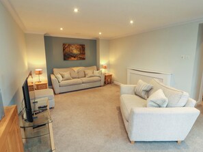 A living room with a sofa, a TV stand, and a painting on the wall. - Cragfell Cottage (Windermere)