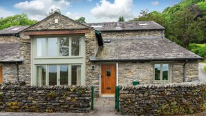 A stone house with a large window and a wooden door. - Cragfell Cottage (Windermere)