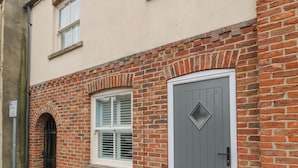 Un bâtiment en briques avec une porte grise et une fenêtre dotée de volets.