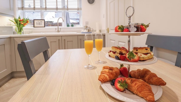 Une table dressée pour le petit-déjeuner, avec des croissants, des fraises et des verres de jus.
