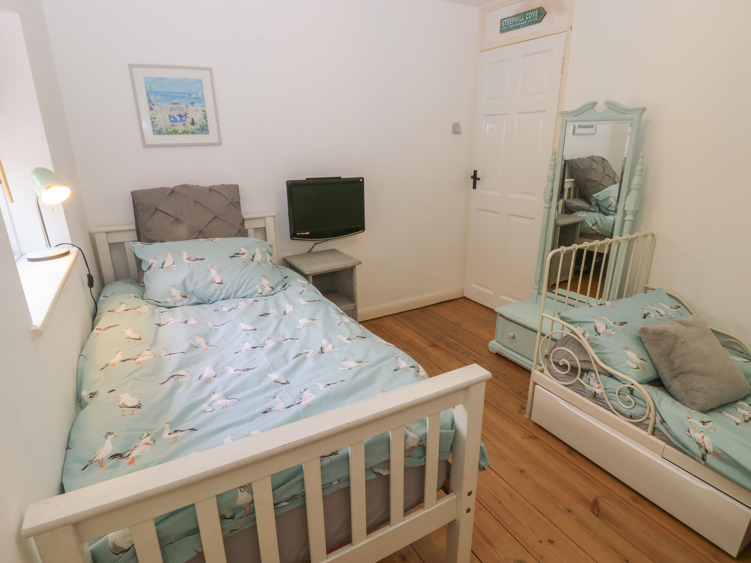 Un dormitorio con una cama, televisión, cómoda y espejo.