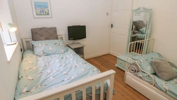 Un dormitorio con una cama, televisión, cómoda y espejo.