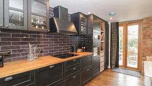 A modern kitchen with dark cabinetry, a wooden countertop, and a built-in oven. - The Courtyard - Hilltop Barn (Blandford Forum)