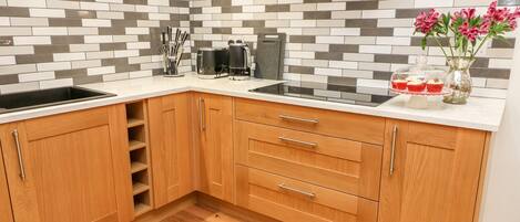 A kitchen with a modern design, featuring a tiled backsplash, wooden cabinets, and a stainless steel range hood.