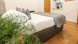 A bedroom with a bed, a window with a view, and a door. - Macaw Cottages No 4 (Kirkby Stephen)