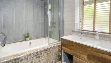 Un baño moderno con ducha de vidrio, una bañera independiente y un tocador con espejo.
