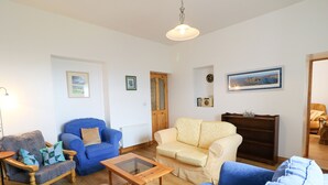 A living room with a blue sofa, a beige sofa, a wooden coffee table, and a blue armchair. - Ard an Phíobaire (Bunbeg)