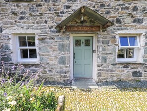 A stone cottage with a green door, two small windows, and a sign above the door reading "Yew Tree Cottage". - Yew Tree Cottage Borrowdale (Keswick)