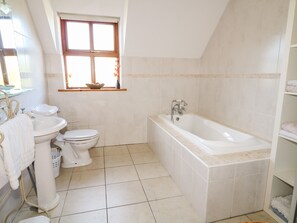 A bathroom with a bathtub, toilet, sink, and a window with a view of the outdoors. - Crolly Home (Crolly)