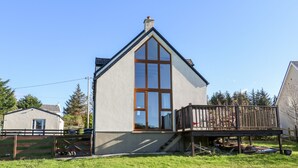 A small, single-story house with a steeply pitched roof and a large window. - Crolly Home (Crolly)