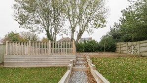 A wooden deck with steps leading to a gravel path surrounded by grass and trees. - Flat 2, 38 Preston Road (Weymouth)