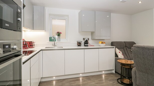 A modern kitchen with white cabinetry, a built-in oven, and a coffee machine. - Flat 2, 38 Preston Road (Weymouth)