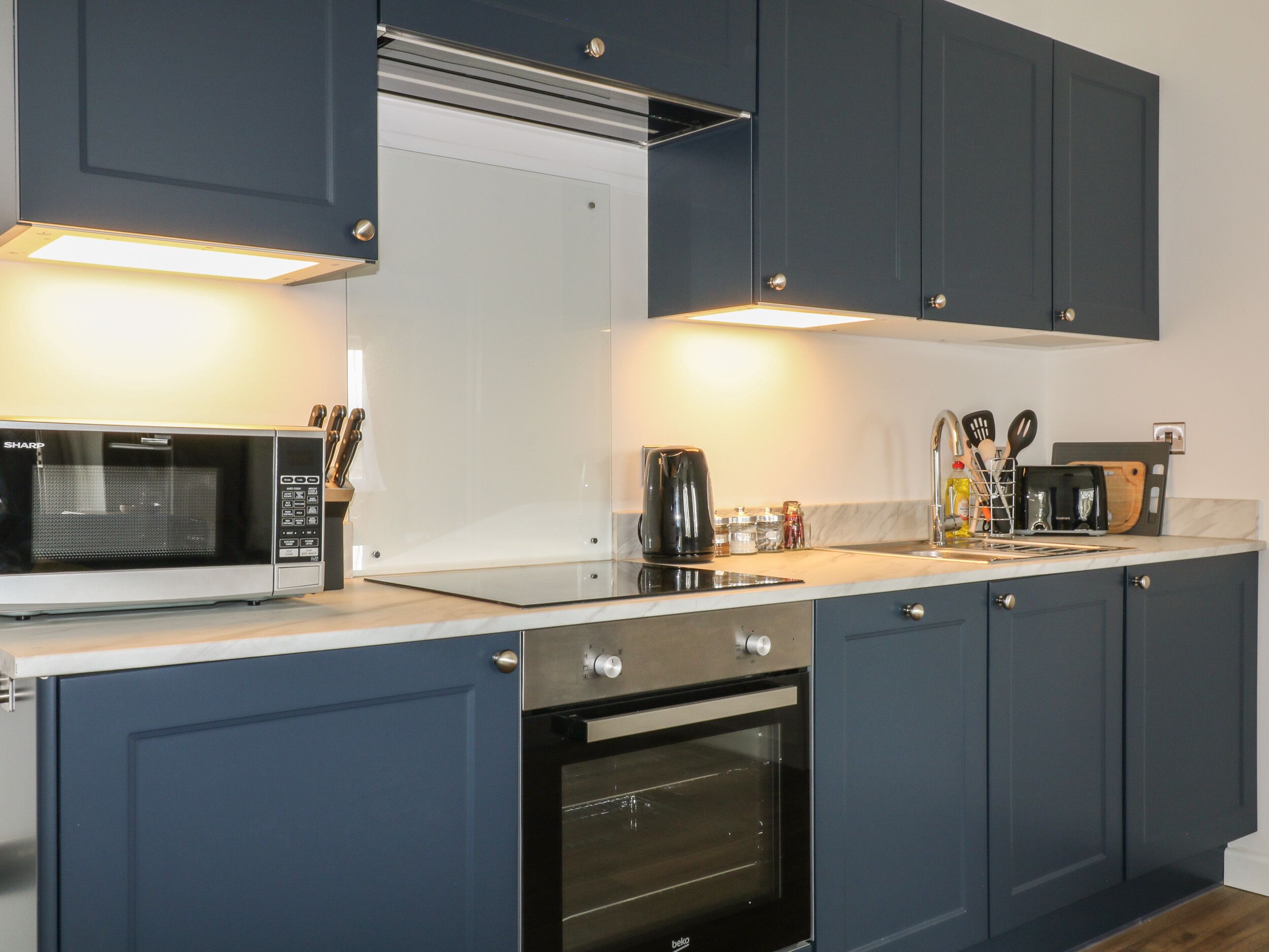 A modern kitchen with a built-in microwave, oven, and coffee maker.
