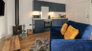 Ein gemütlicher Wohnraum mit einer Küche, einer Couch mit Kissen, einem Holztisch und einem Kamin.