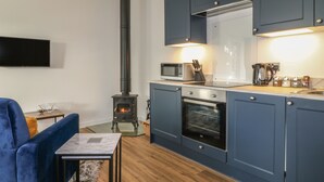 Eine kompakte Küche mit Holzofen, Mikrowelle, Backofen und modernen Schränken.