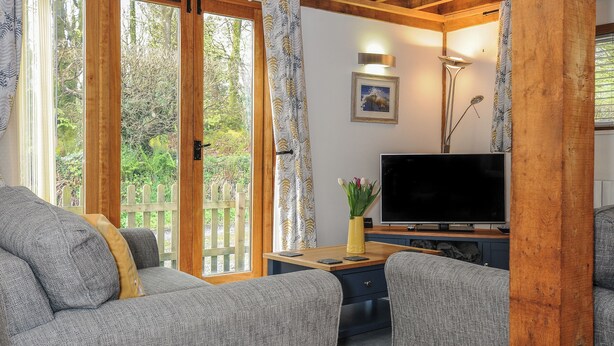 Een gezellige woonkamer met een bank, een televisie en een houten tafel met een bloemenvaas.