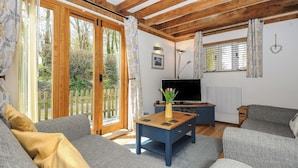 Een gezellige woonkamer met een houten plafond, een televisie en een bank.