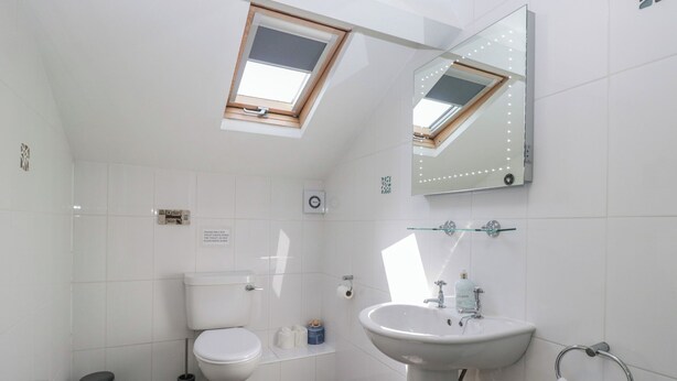 A modern bathroom with a skylight, toilet, bidet, and a sink with a towel ring. - Woodside West (Windermere)