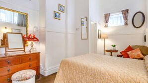 A bedroom with a bed, a dresser, a mirror, and a window with curtains. - Clooneavin Apartment 2 (Lynmouth)