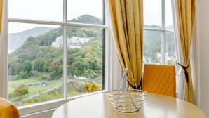 A round table with a metal tray in the center, positioned in front of a window with curtains. - Clooneavin Apartment 2 (Lynmouth)