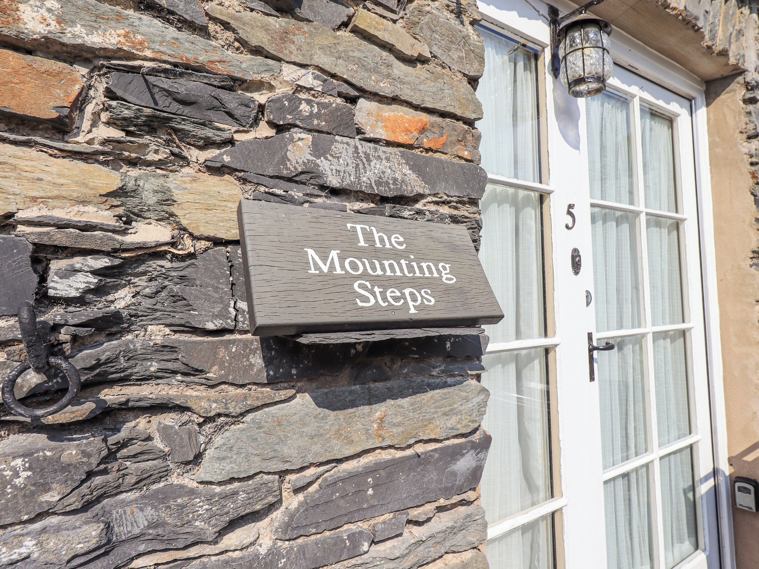 Een stenen muur met een bord waarop staat 'The Mounting Steps'.