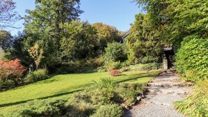 A well-maintained garden with a gravel path leading to a stone structure. - The Mounting Steps (Ambleside)