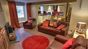 Un salon avec un canapé en cuir marron, un tapis rouge et une table basse en bois.