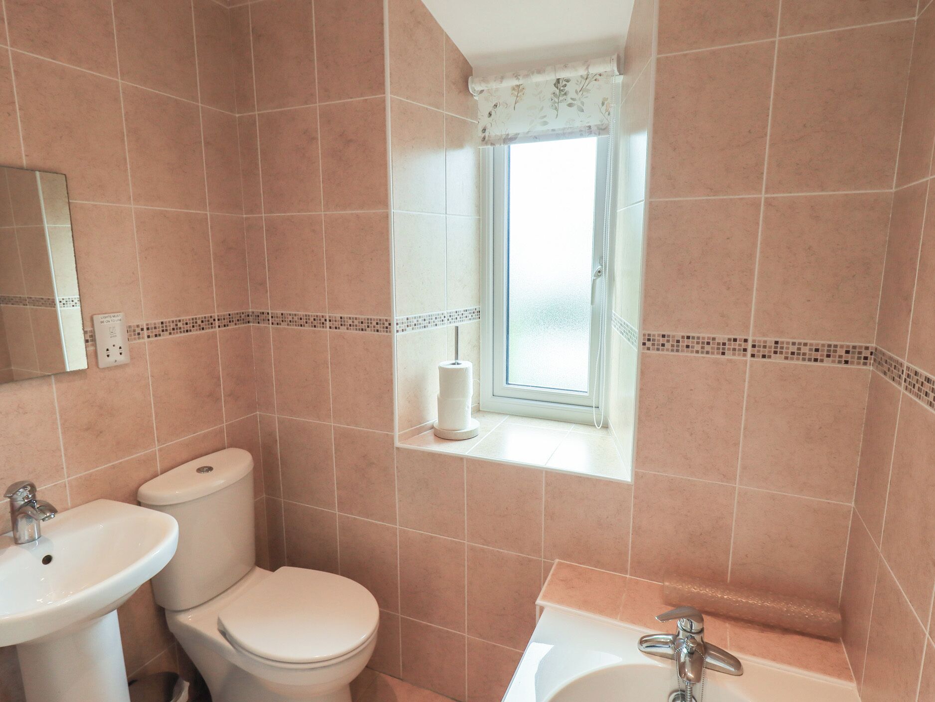 Une salle de bain comprenant des toilettes, un lavabo et une baignoire, une fenêtre avec vue et un miroir au mur.